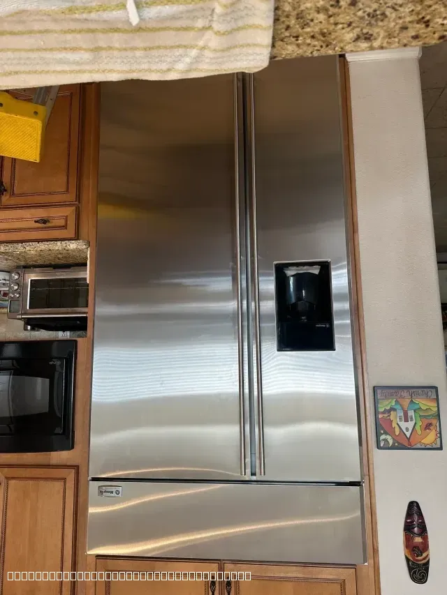 A large stainless steel side-by-side refrigerator built into wooden kitchen cabinets.