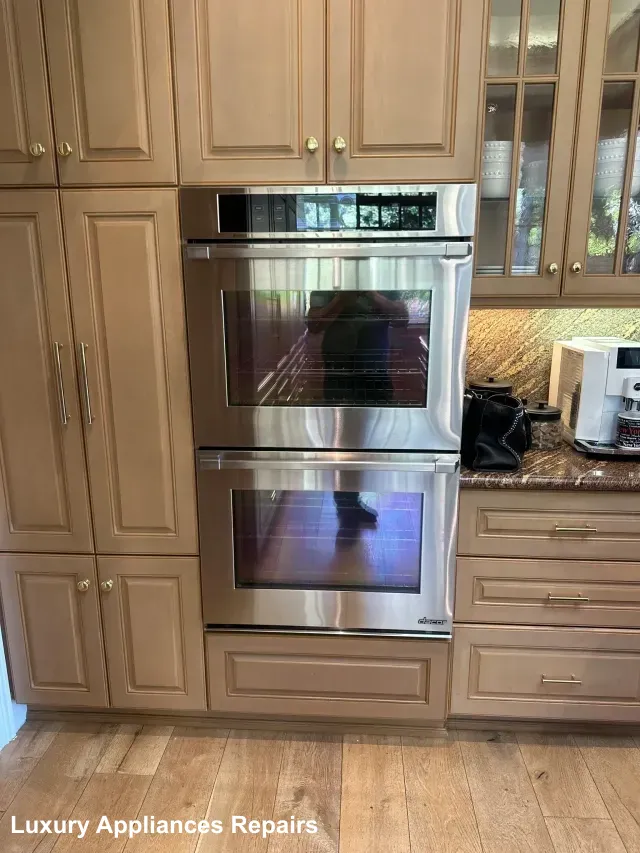 A pair of stainless steel built-in ovens installed in custom wooden kitchen cabinets.