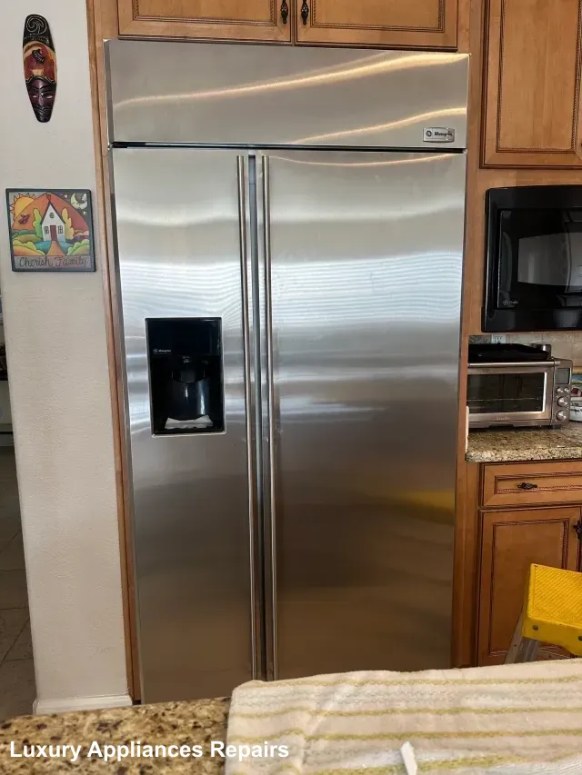 A large built-in stainless steel refrigerator integrated into wooden kitchen cabinets.
