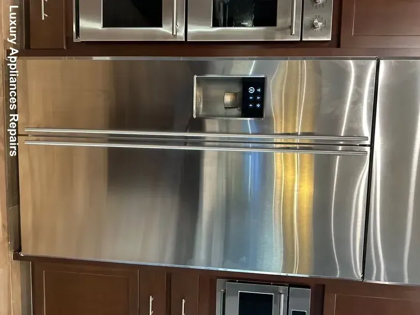 A high-end stainless steel side-by-side refrigerator built into dark wood kitchen cabinets.