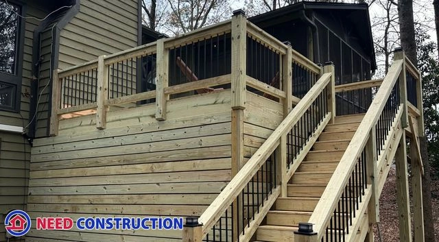 A newly built wooden deck with black metal railings and a staircase by Need Construction.