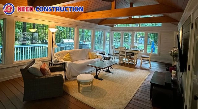 A luxurious sunroom with large windows, vaulted wood ceilings, and comfortable living room furniture.