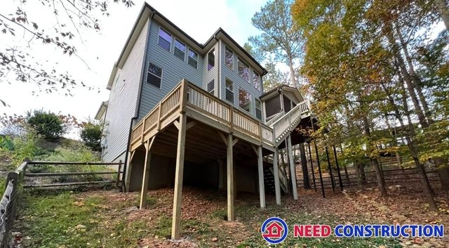 A large elevated wooden deck attached to the rear of a two-story home with blue siding.