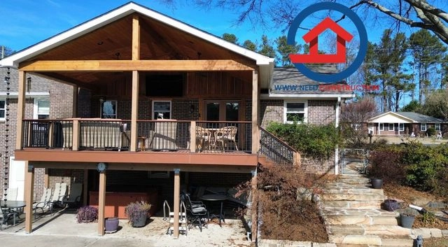A large custom-built covered deck with a wood ceiling and stone walkway by Need Construction.