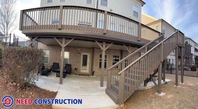 A large brown elevated deck with a staircase and a dry patio area underneath featuring an underdeck system.