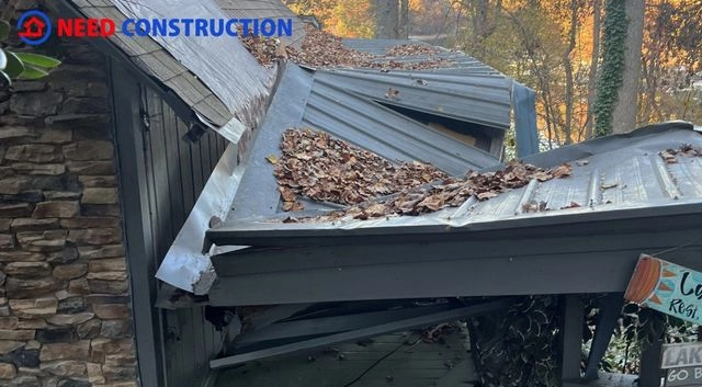 Severe damage to a metal roof with collapsed panels and leaf debris.