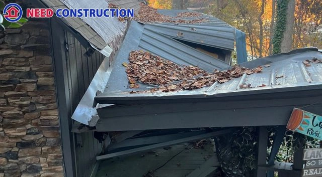 Severely damaged and collapsed metal roof with fallen leaves and structural debris.