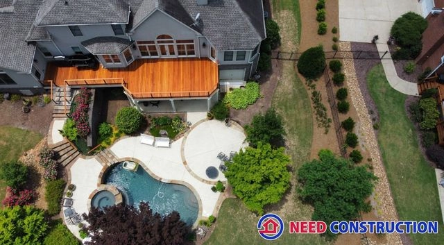 Aerial view of a custom wood deck, swimming pool, and patio designed by Need Construction.
