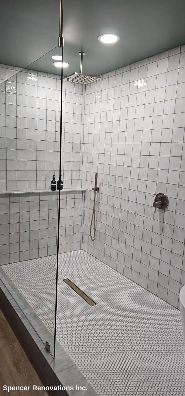A modern bathroom featuring a white freestanding bathtub, white subway tiles, dark green wall, and white hexagonal floor tiles.