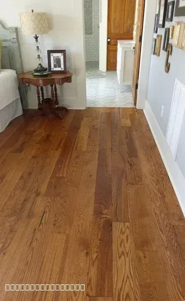 Newly installed hardwood flooring transitioning into a tiled bathroom floor in a home remodel.