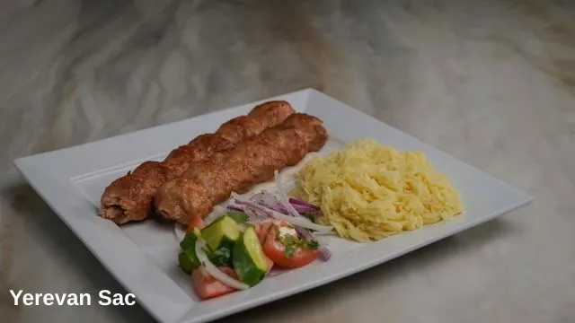 A beautifully plated meal featuring two long, succulent grilled ground meat kebabs, a side of fluffy yellow rice pilaf, and a fresh garden salad made with — Yerevan Sac, Carmichael CA