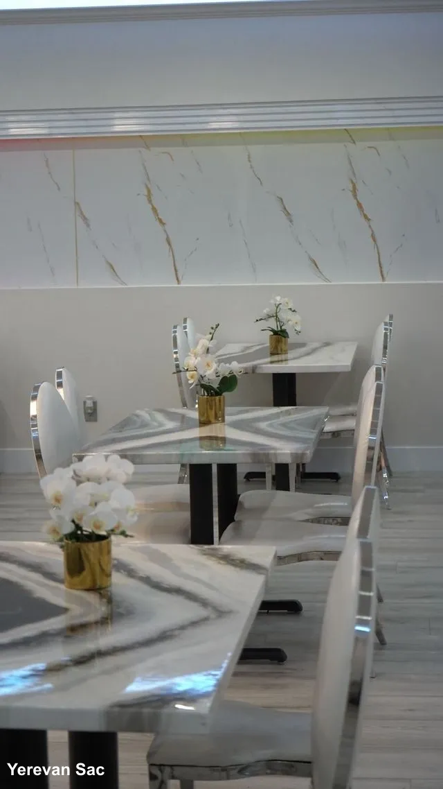 A view of the dining area at Yerevan Sac, showcasing modern marble-patterned tables and white chairs with silver trim