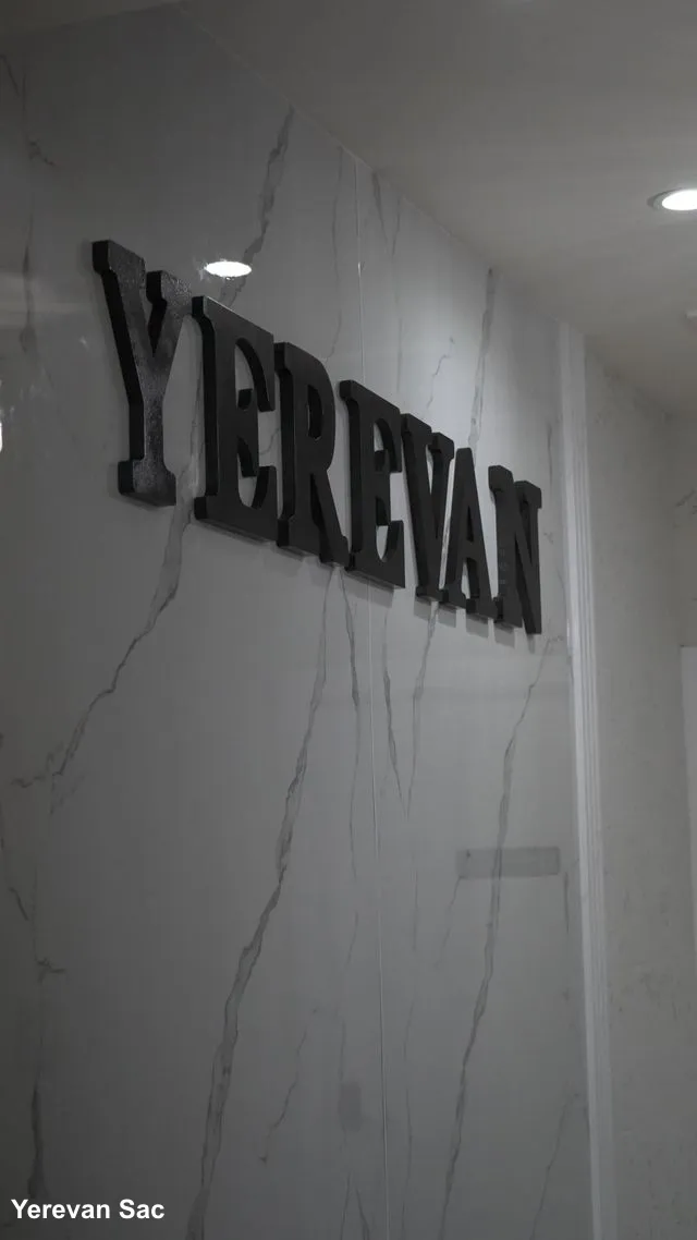 A close-up shot of the 'YEREVAN' sign in bold, black 3D letters mounted on a polished white marble wall with grey veining — Yerevan Sac, Carmichael CA