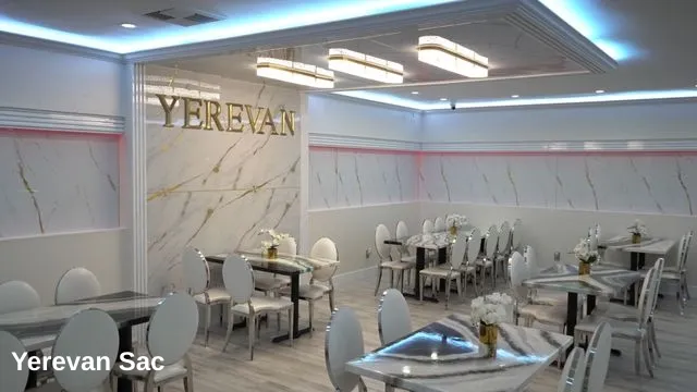 The interior of Yerevan Sac restaurant showcases a sophisticated dining area with white marble-patterned walls and gold accents
